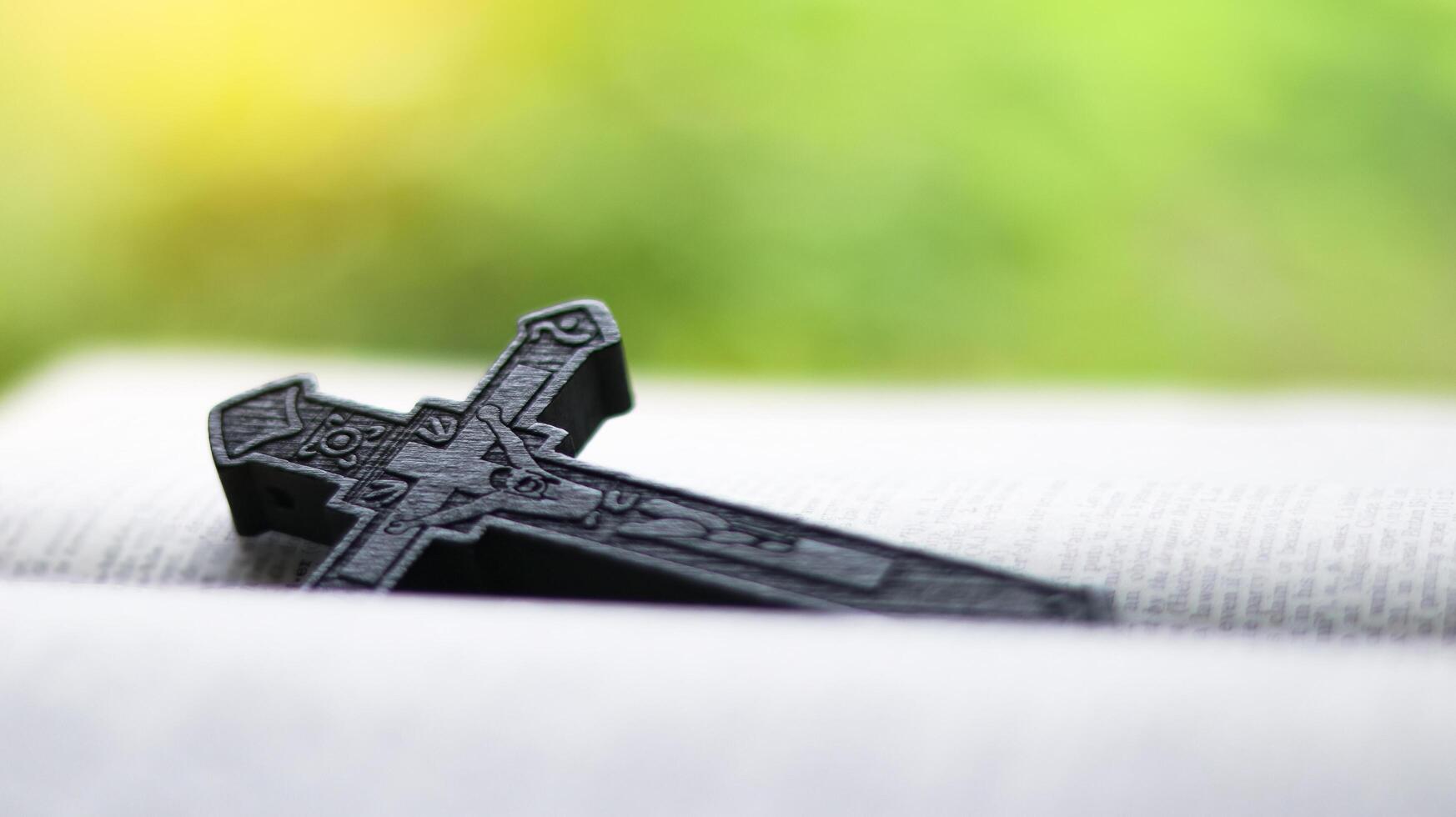 Dark brown wooden cross on an old open book symbolizing the spread of Jesus Christs love among Christians reflecting faith devotion and the importance of Christian teachings. photo