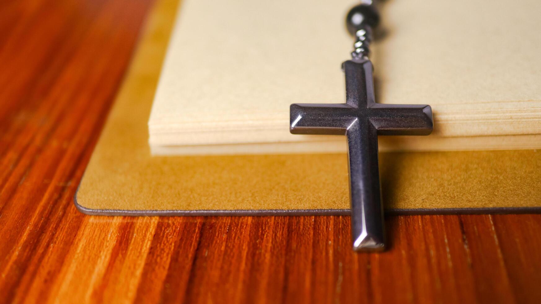 Dark metal cross on an old open book symbolizing the spread of Jesus Christs love among Christians reflecting faith devotion and the importance of Christian teachings. photo