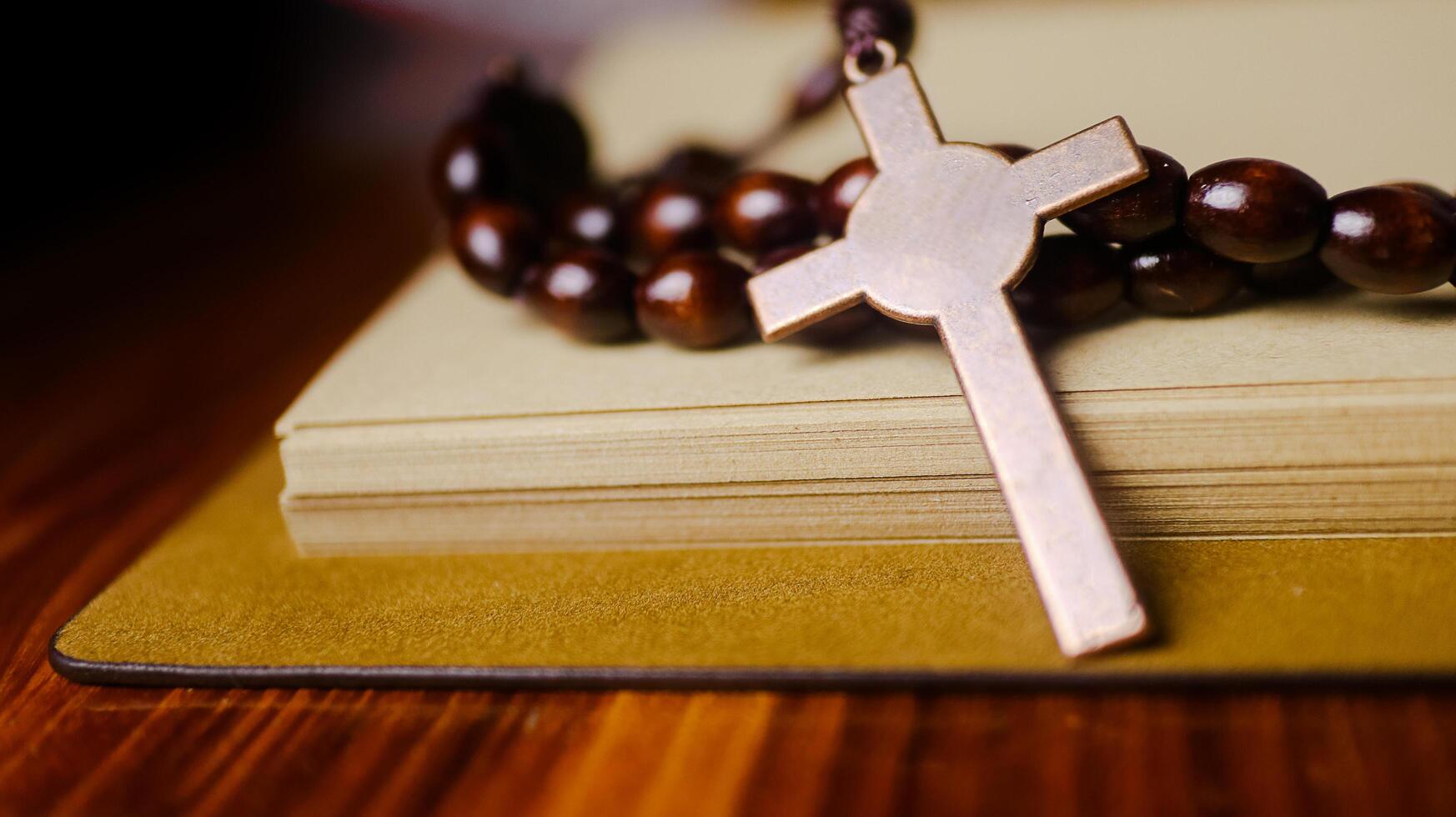 Shiny copper cross leaning against an old open book symbolizing the spread of Jesus Christs love among Christians reflecting faith devotion and the importance of Christian teachings. photo