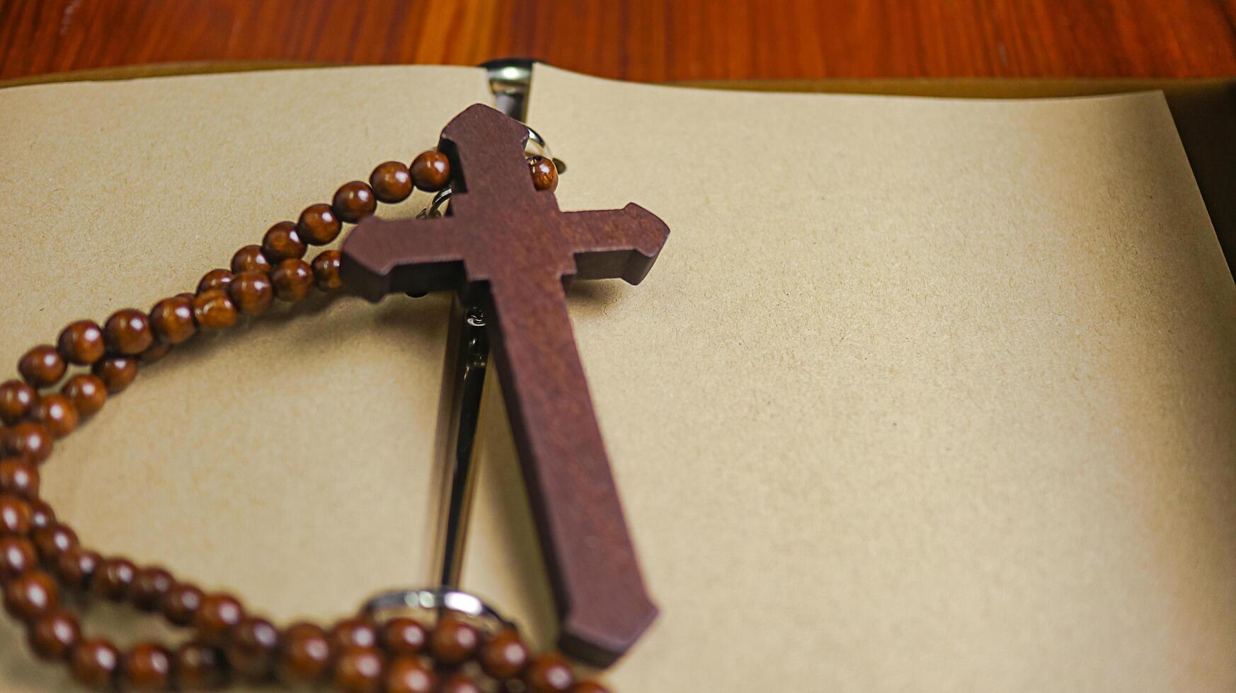 Dark red wooden cross leaning against an old open book symbolizing the spread of Jesus Christs love among Christians reflecting faith devotion and the importance of Christian teachings. photo