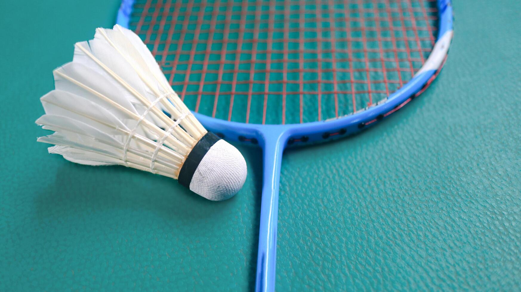 White badminton shuttlecocks and badminton rackets on green floor indoor badminton court. Concept for badminton competition and its lovers. photo