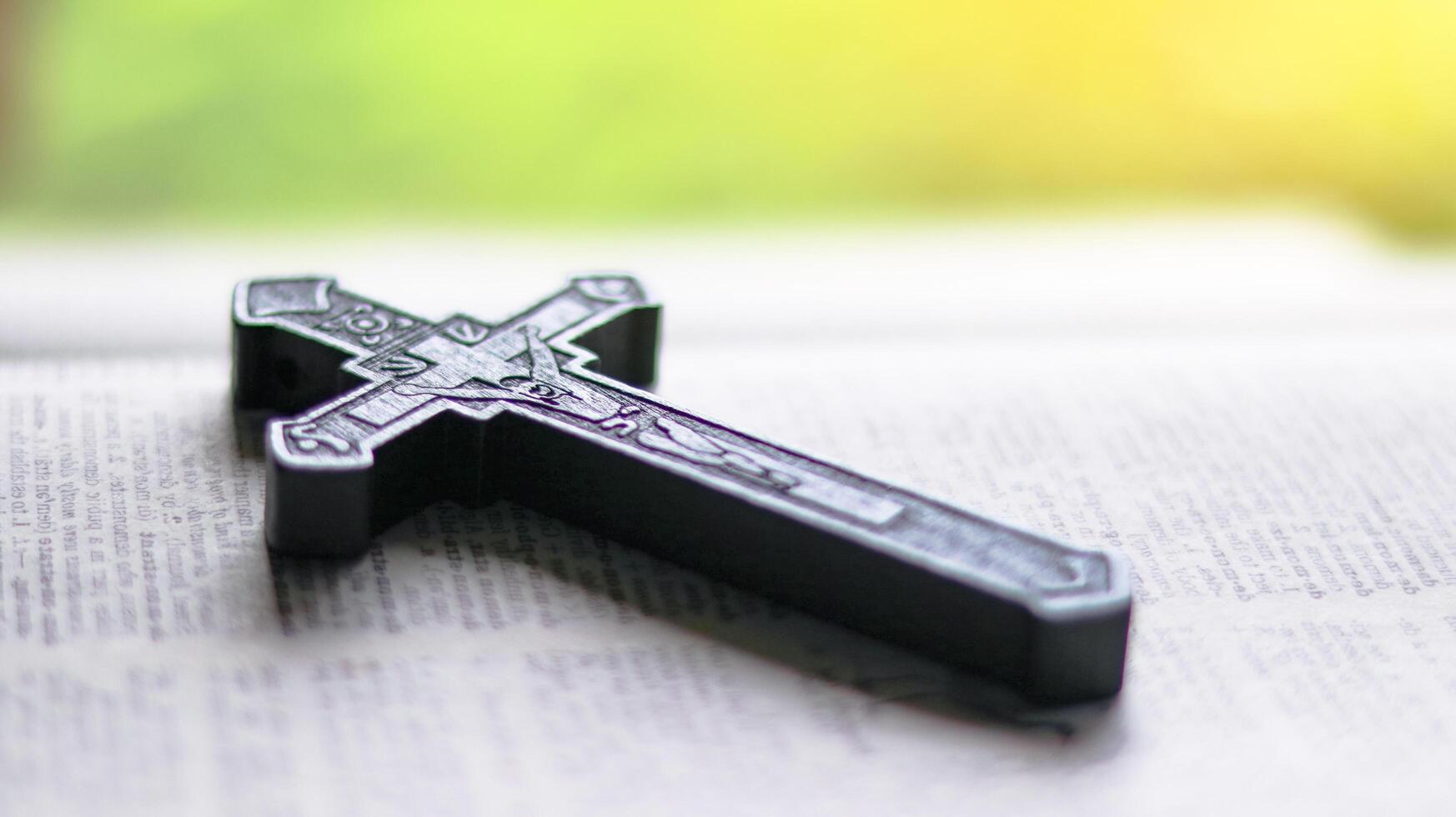 Dark brown wooden cross on an old open book symbolizing the spread of Jesus Christs love among Christians reflecting faith devotion and the importance of Christian teachings. photo