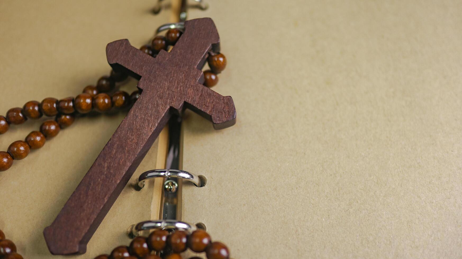 Dark red wooden cross leaning against an old open book symbolizing the spread of Jesus Christs love among Christians reflecting faith devotion and the importance of Christian teachings. photo