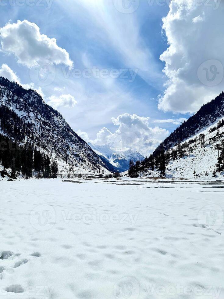 A snowy mountain landscape with a lake and trees photo