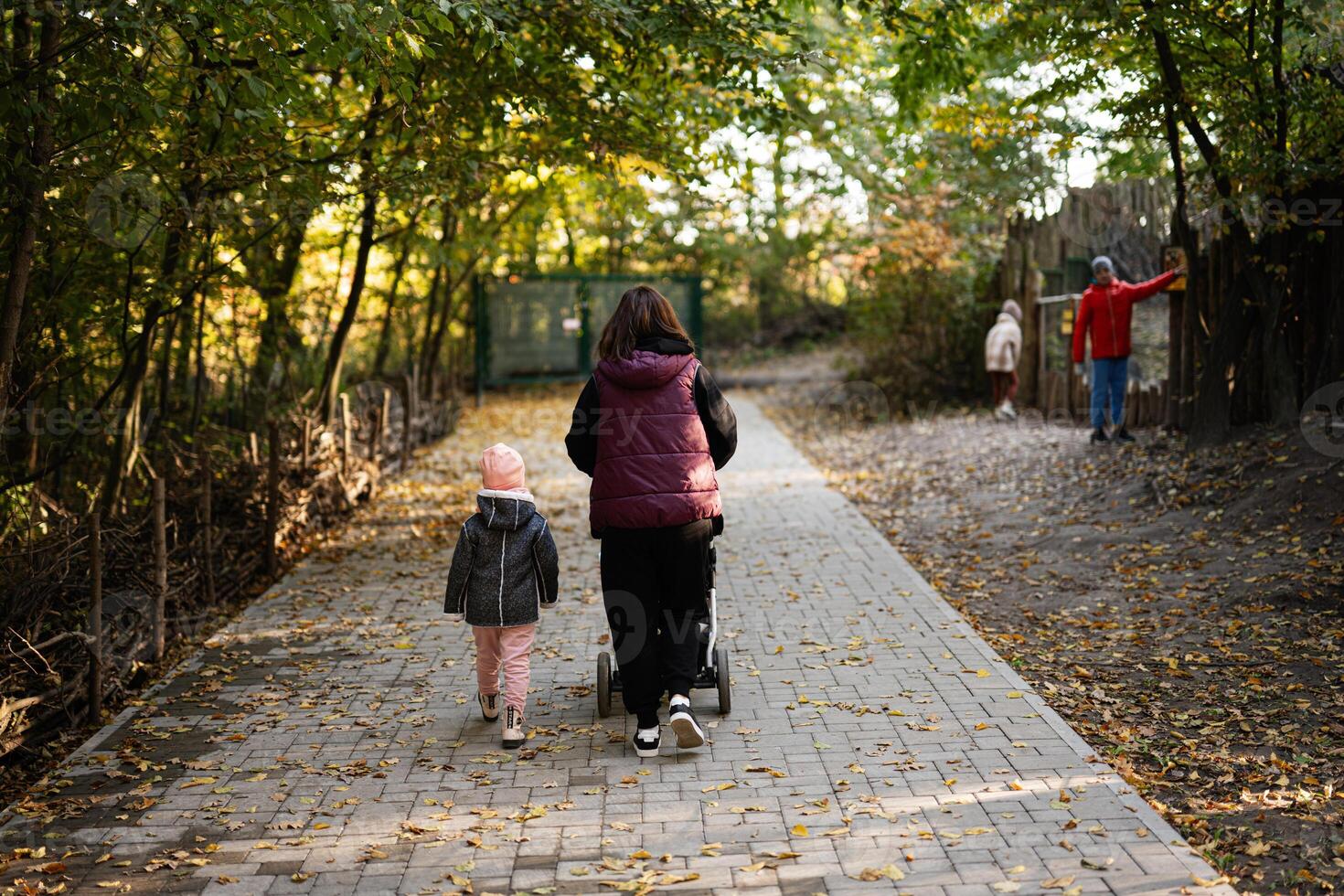 Mother and child strolling through a peaceful autumn forest path photo