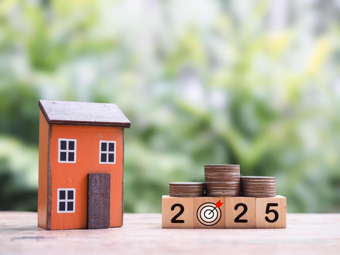 Miniature house, Wooden blocks with the number 2025 and stack of coins. The concept of saving money for house, Property investment, House mortgage, Real estate in year 2025 photo