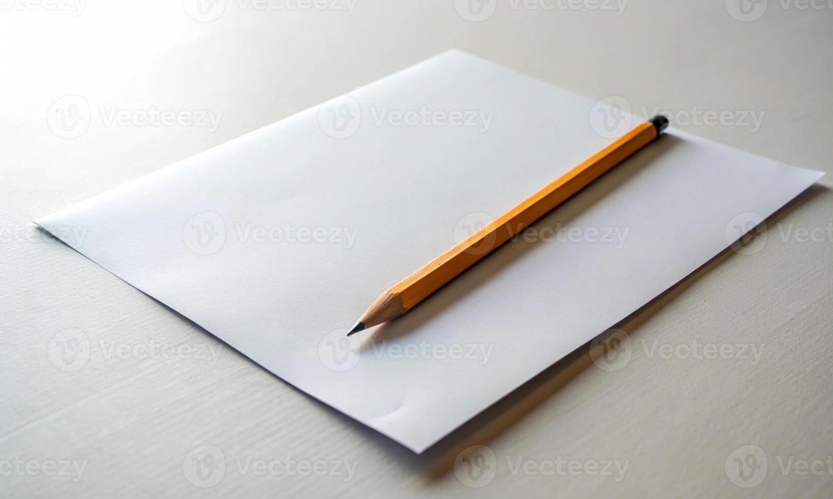 A yellow graphite pencil is lying on an empty piece of paper photo