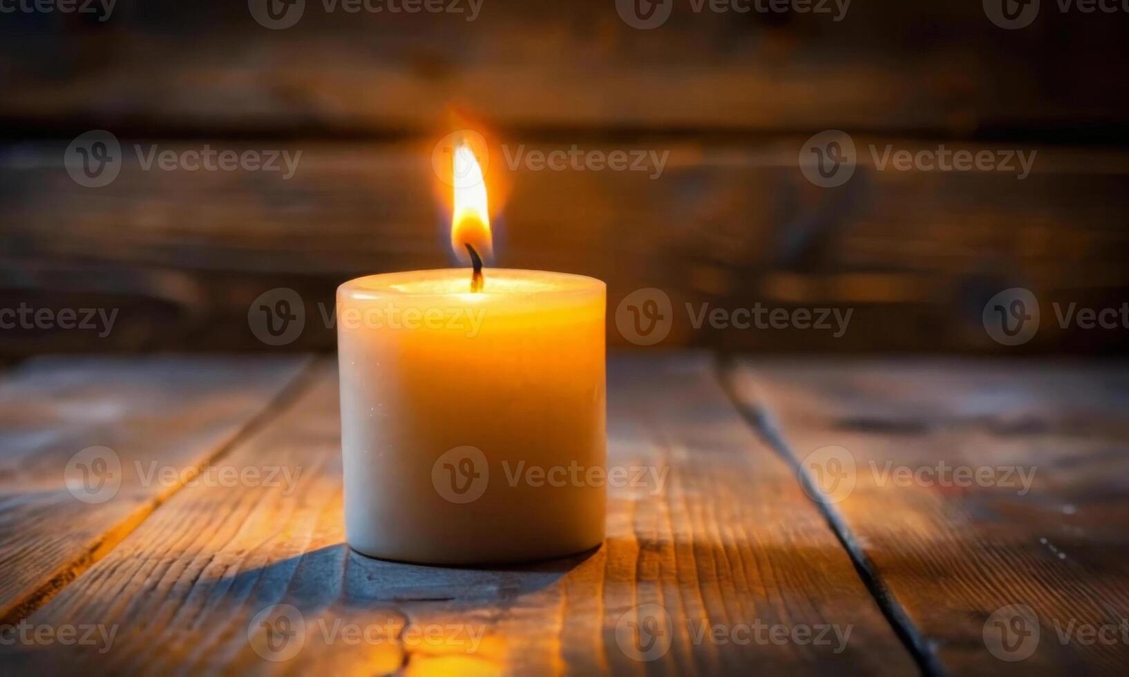 A burning wax candle on a wooden table on an abstract background photo