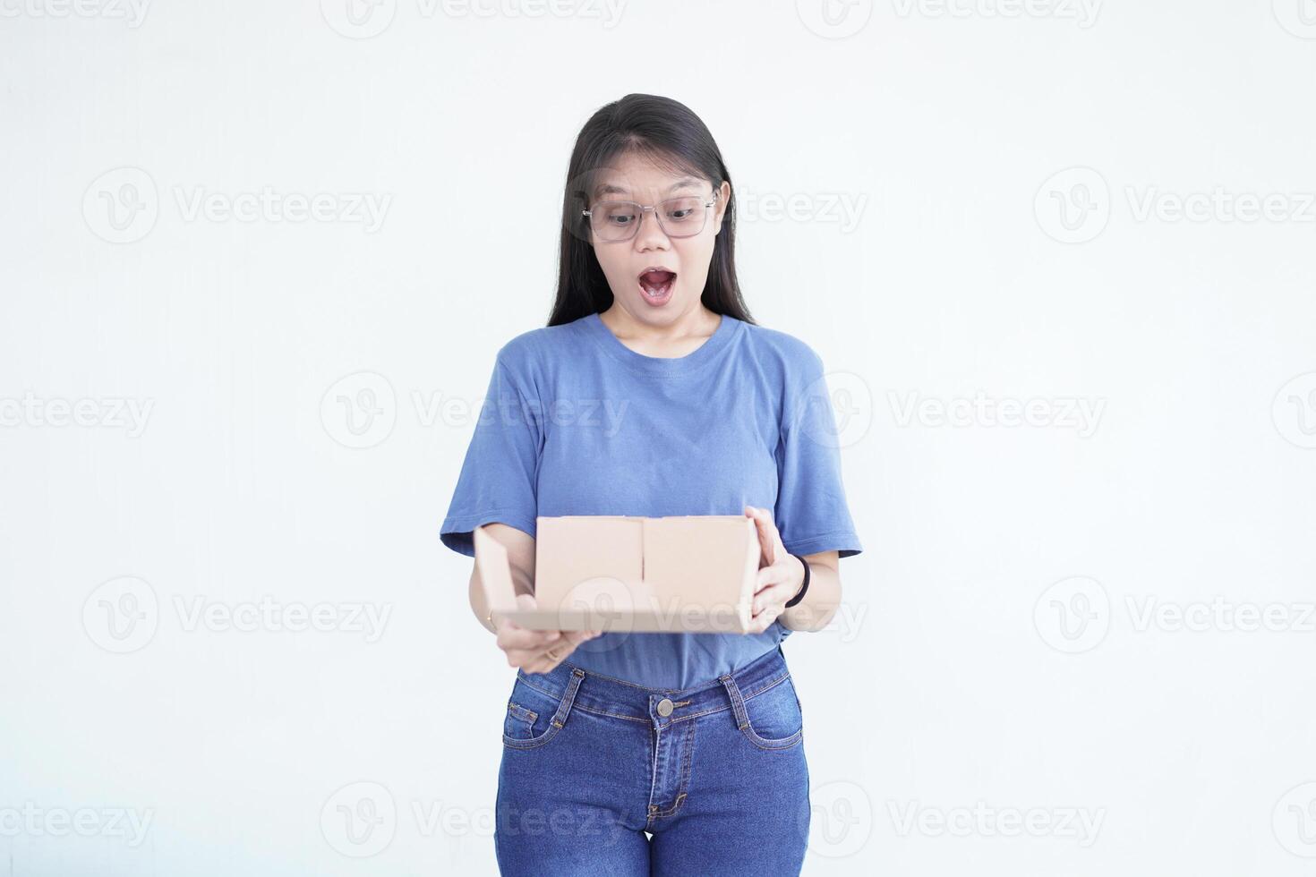 beautiful Asian woman holds a box package, displaying a shocked wow face expression against a white background photo