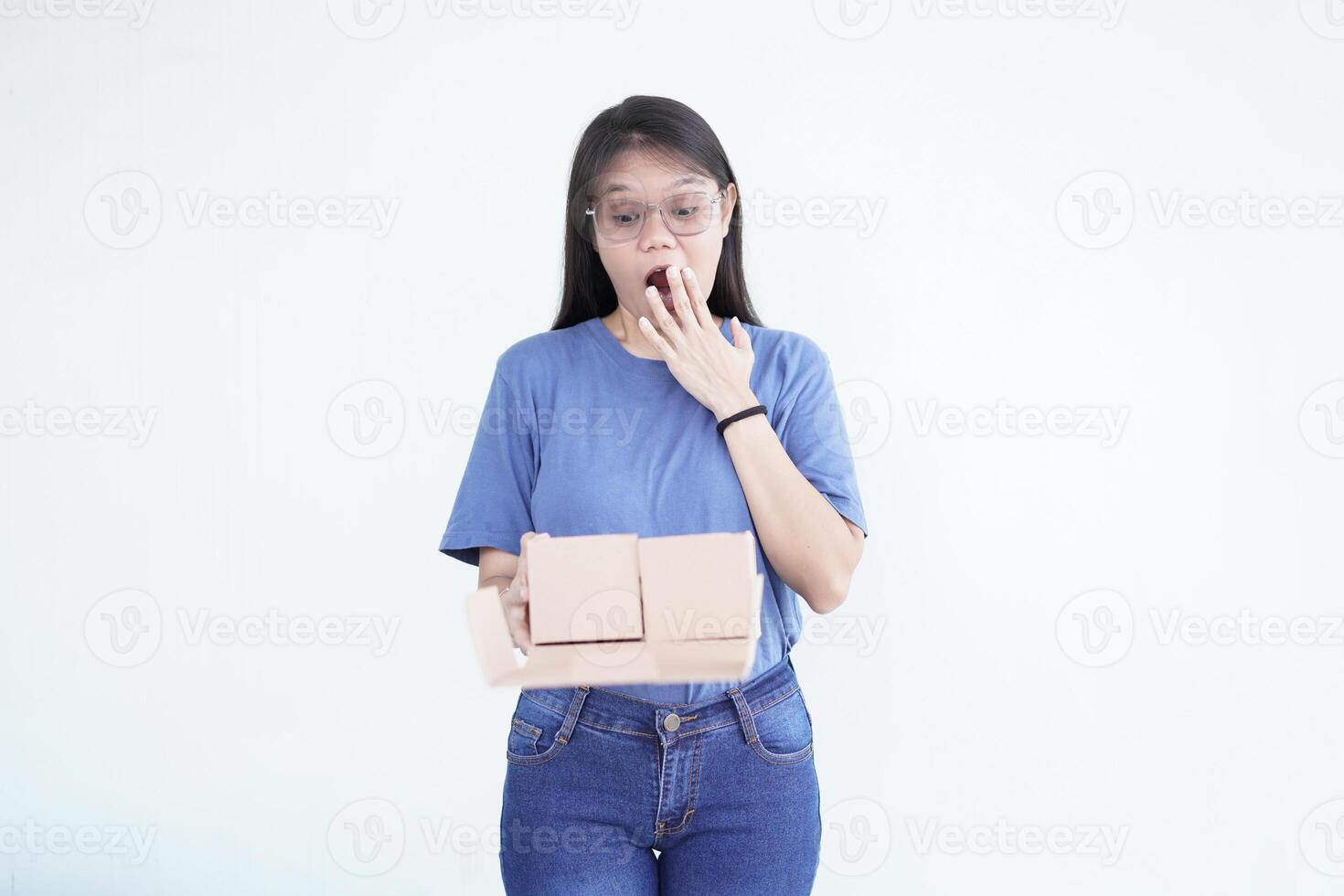 beautiful Asian woman holds a box package, displaying a shocked wow face expression against a white background photo