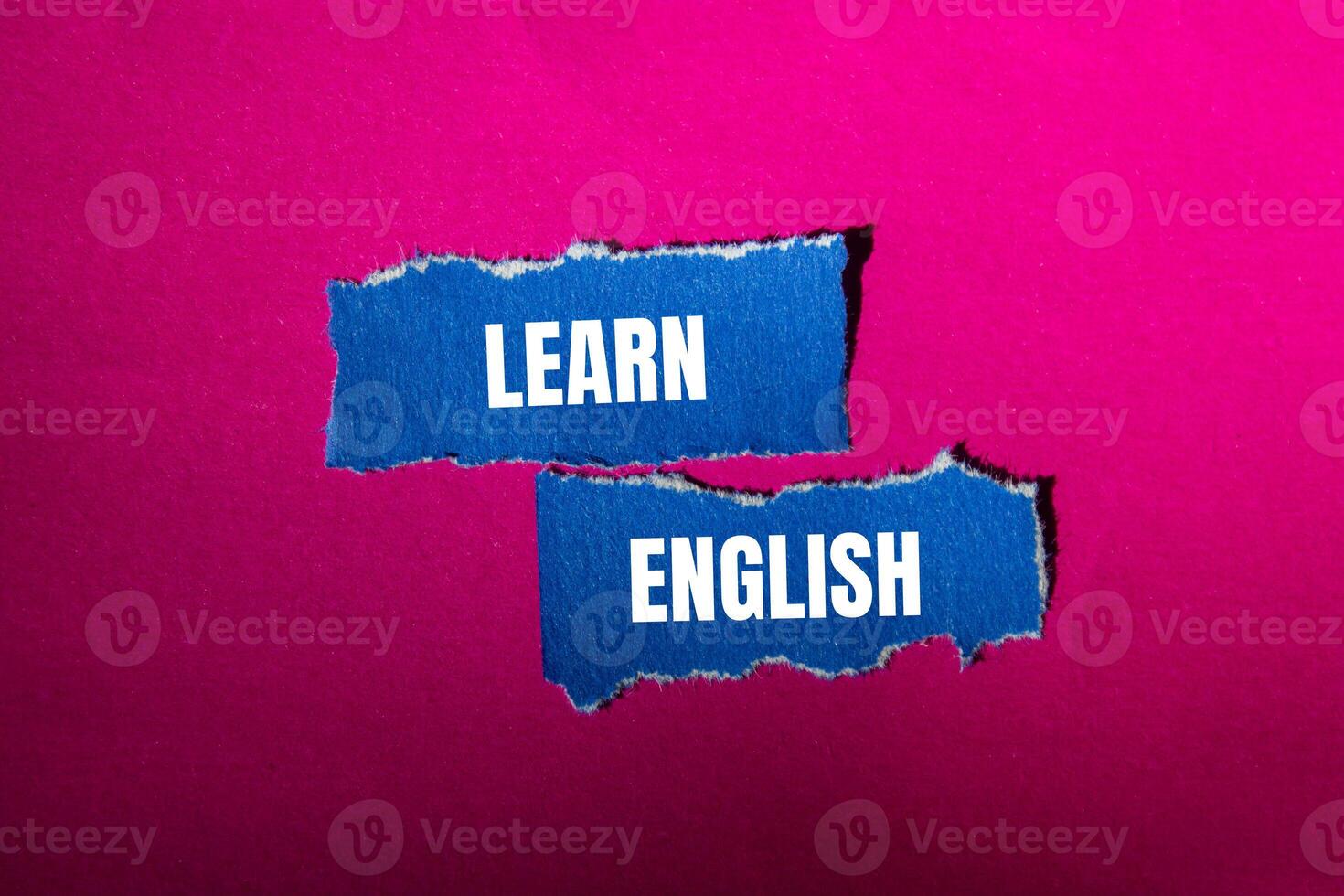 Learn english message written on ripped torn blue paper pieces with pink background. Conceptual learn english symbol. Copy space. photo