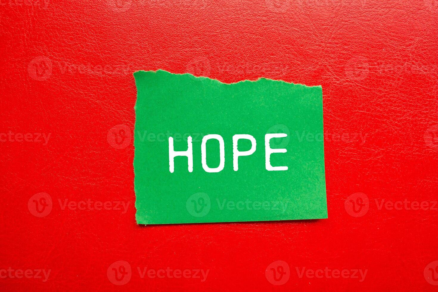 Hope message written on ripped torn green paper piece with red background. Conceptual hope symbol. Copy space. photo