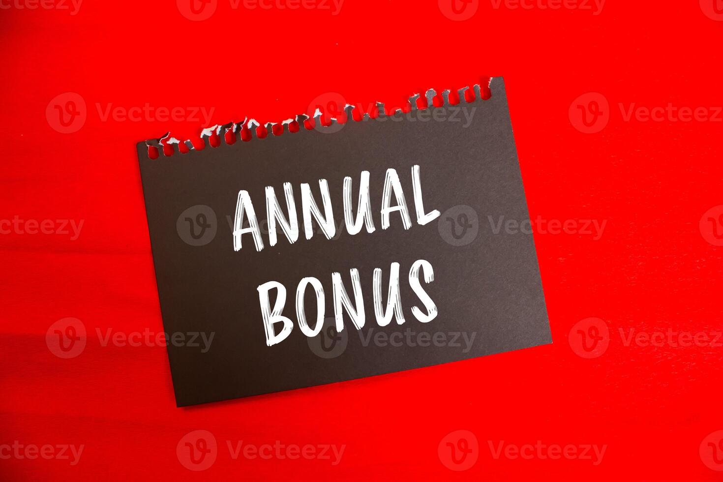 Annual bonus message written on black notebook page paper with red background. Conceptual annual bonus symbol. Copy space. photo