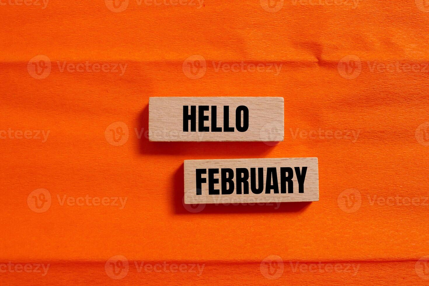 Hello february message written on wooden blocks with orange background. Conceptual hello february symbol. Copy space. photo