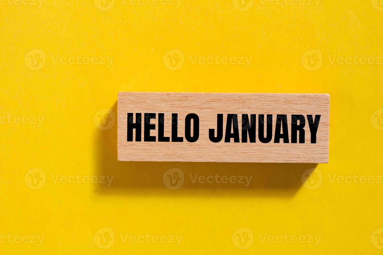 Hello january message written on wooden block with yellow background. Conceptual hello january symbol. Copy space. photo