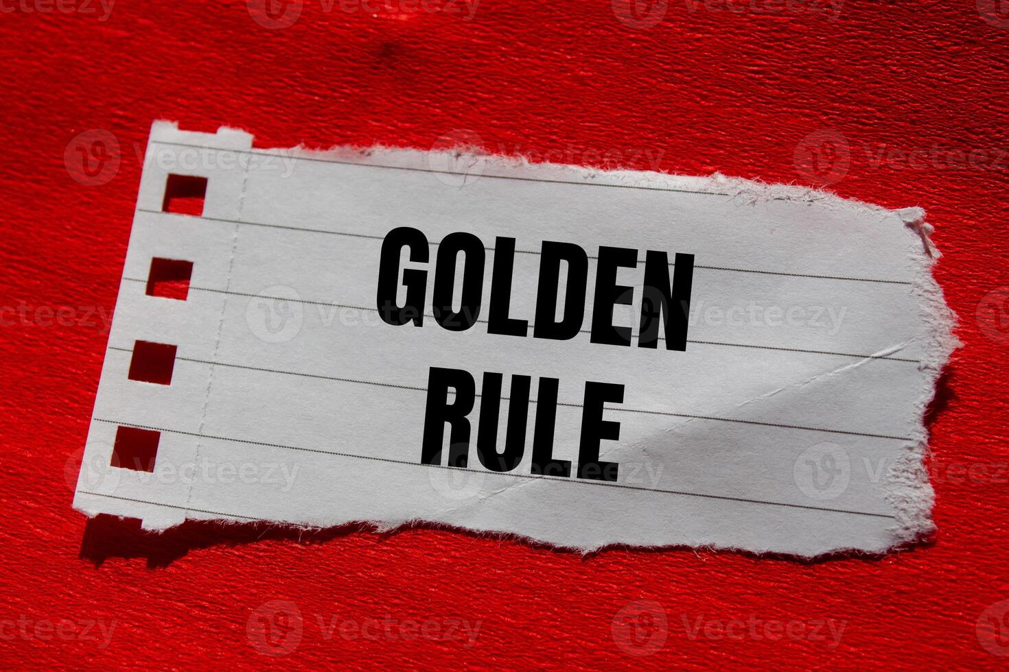 Golden rule message written on ripped torn paper piece with red background. Conceptual golden rule symbol. Copy space. photo