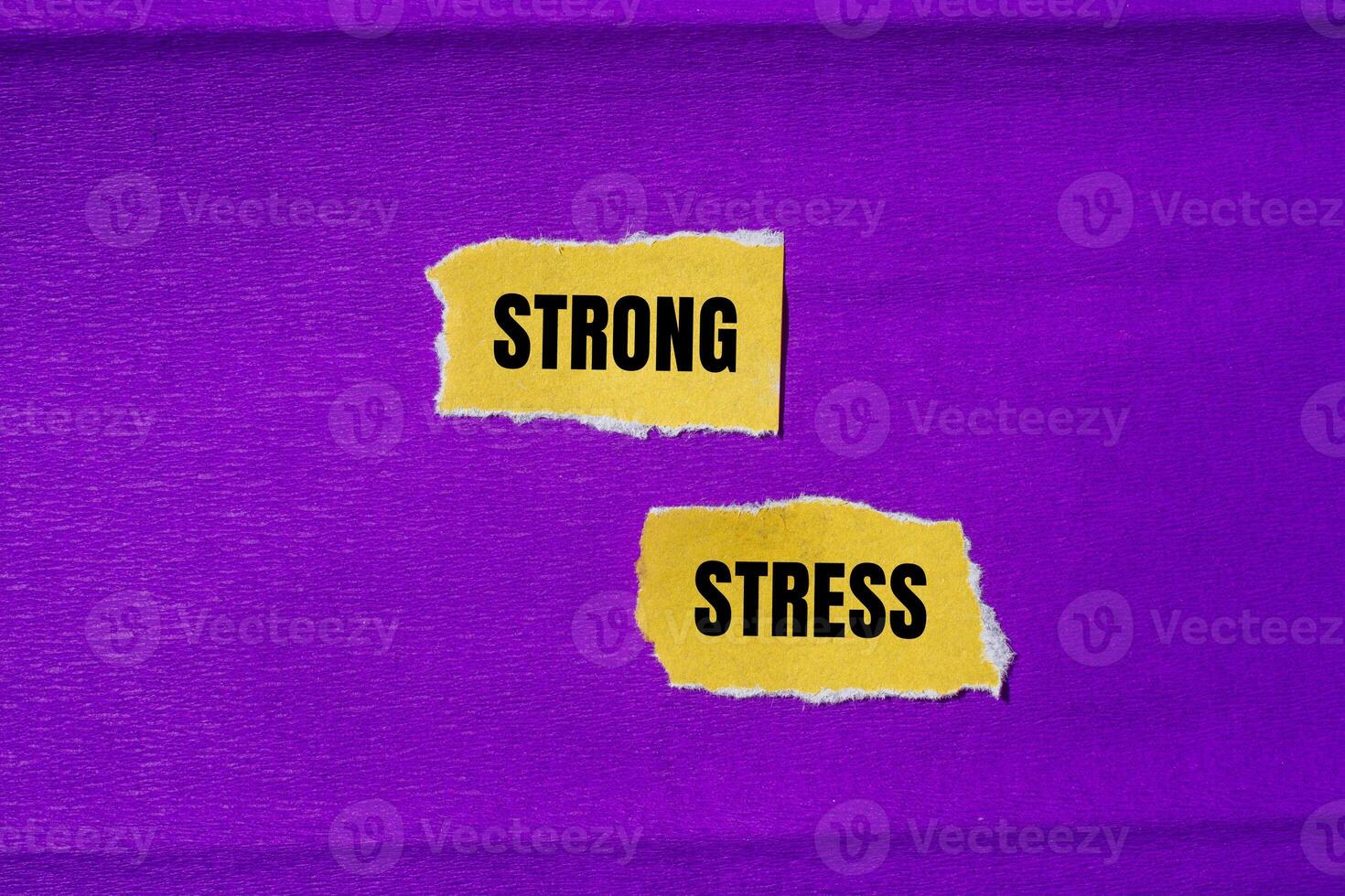 Strong stress message written on ripped torn yellow paper pieces with purple background. Conceptual strong stress symbol. Copy space. photo