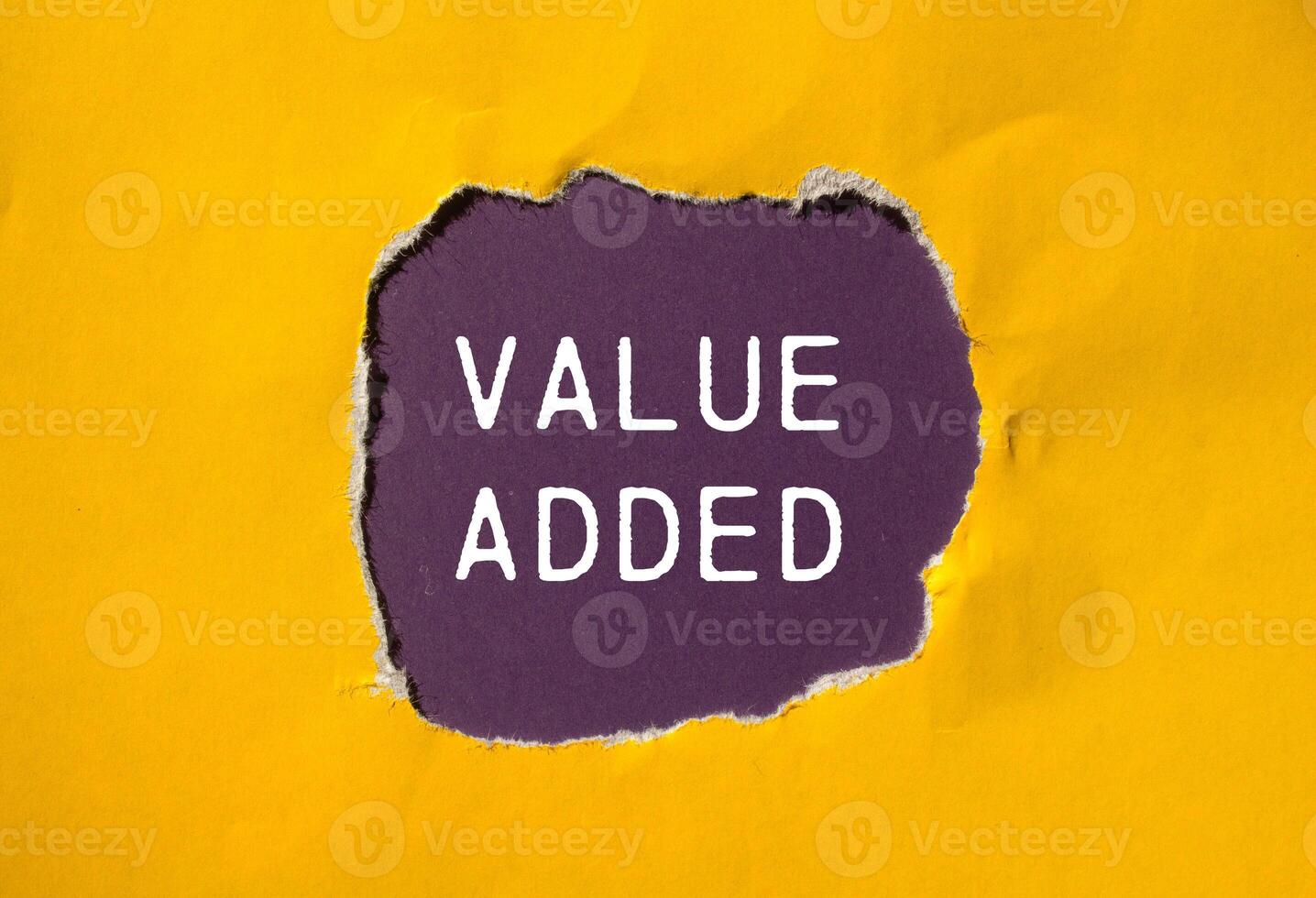 Value added message written on ripped torn yellow paper with purple background. Conceptual value added symbol. Copy space. photo