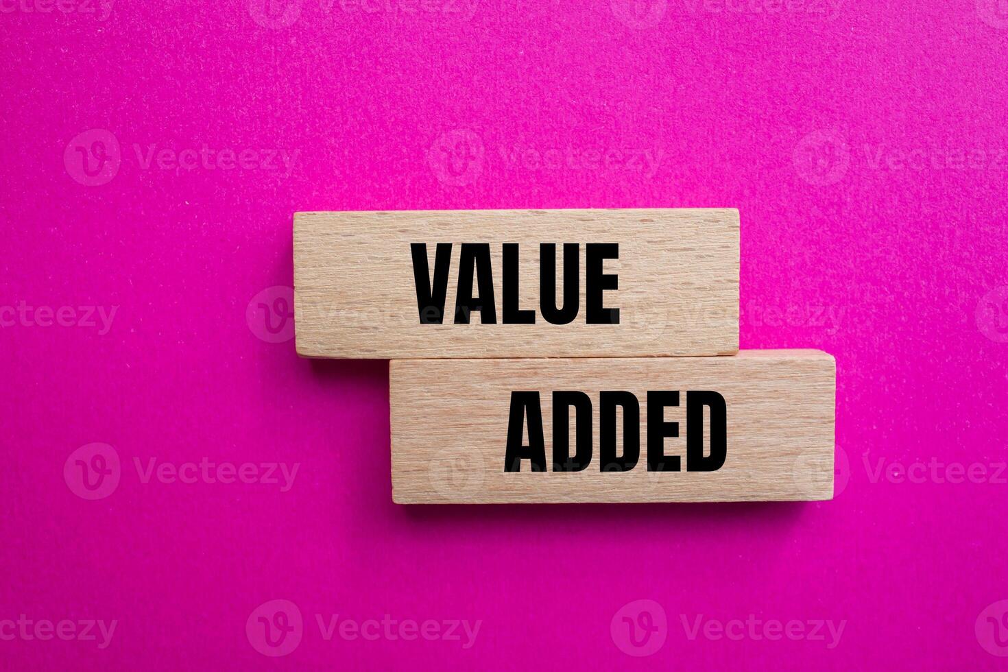 Value added message written on wooden blocks with pink background. Conceptual value added symbol. Copy space. photo