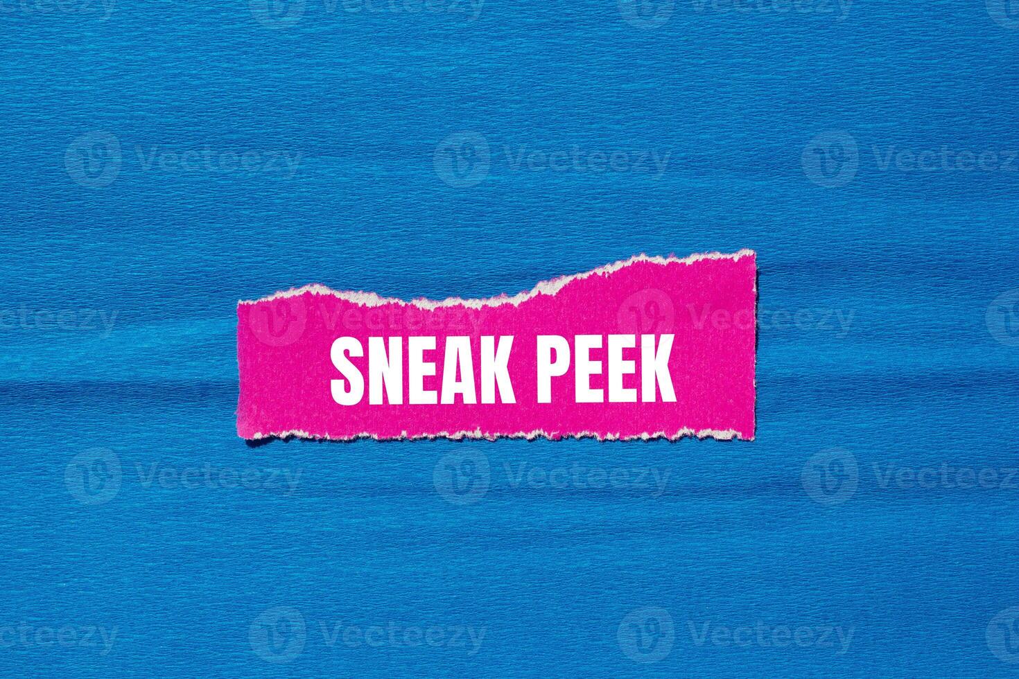 Sneak peek message written on ripped torn pink paper piece with blue background. Conceptual sneak peek symbol. Copy space. photo