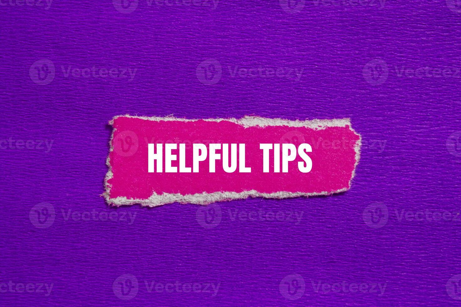 Helpful tips message written on ripped torn pink paper piece with purple background. Conceptual helpful tips symbol. Copy space. photo