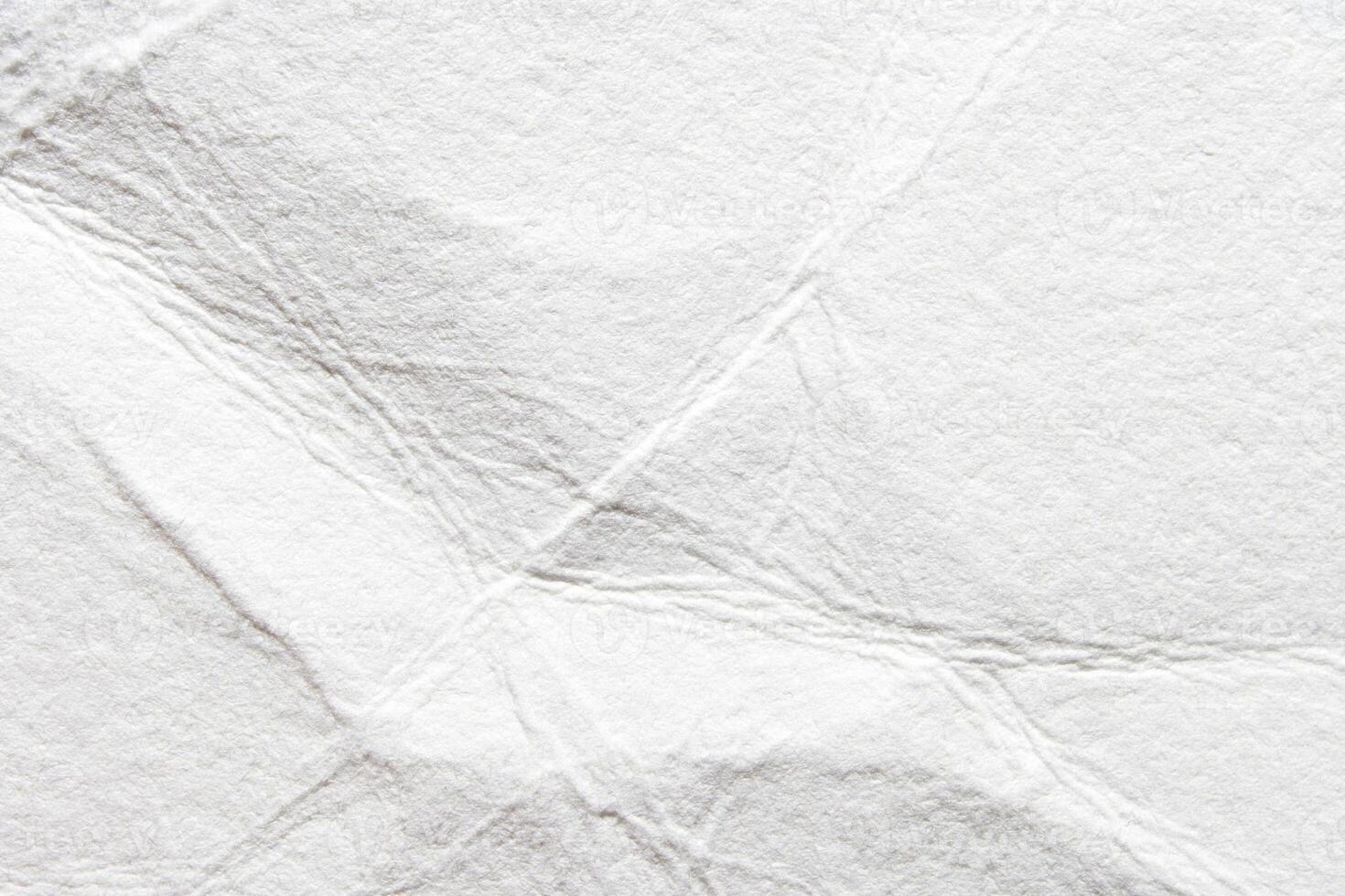 Close-up of crumpled white paper texture with wrinkles and folds for creative background designs. photo