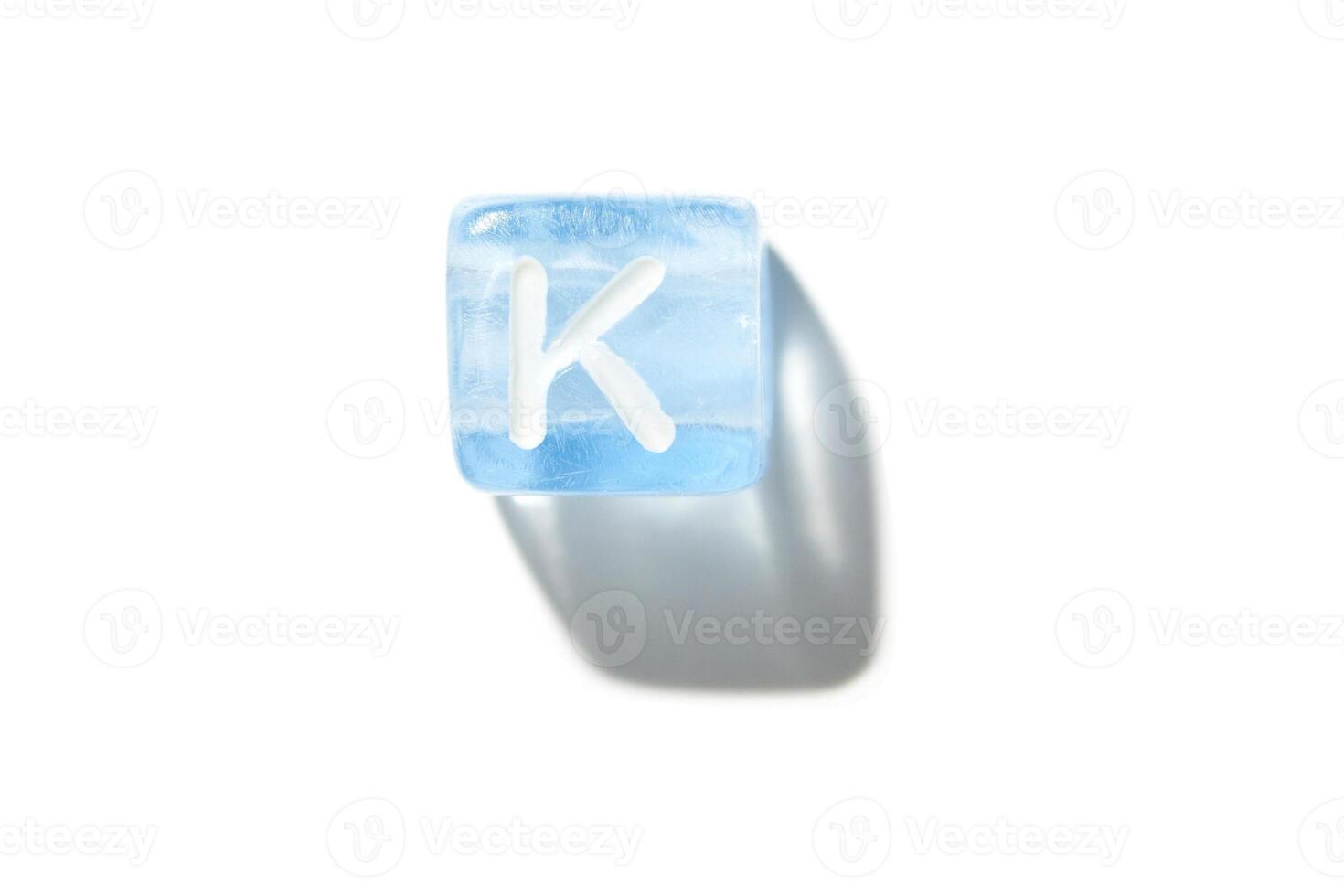 Frozen blue ice cube with letter k and shadow on white background for cool refreshing designs photo