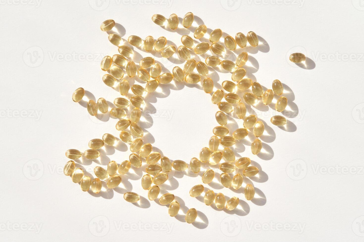 Vitamin d capsules arranged in circle on white surface with shadows and light reflection photo