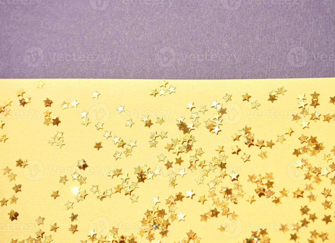 Sparkling gold star confetti scattered on yellow paper background with minimal design elements. photo