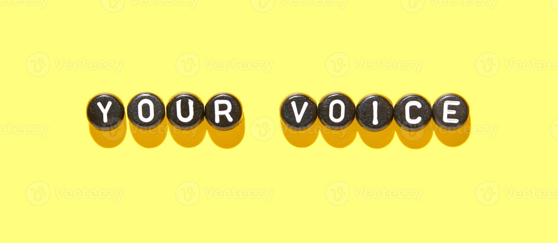 Your voice concept with letter beads on bright yellow background for communication and expression themes. photo