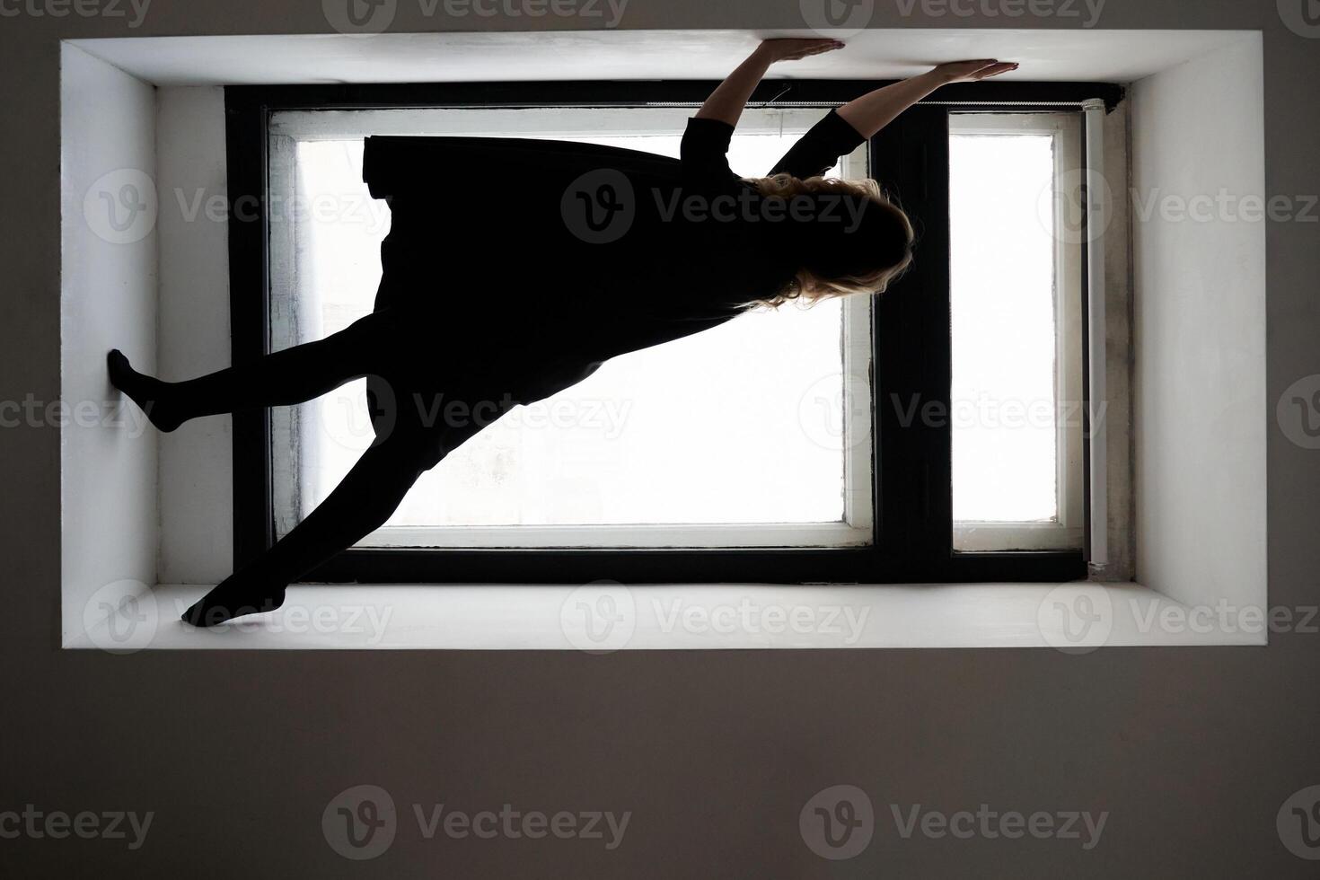 Creative indoor photography. silhouette of a woman balancing gracefully on window ledge in minimalist setting. photo