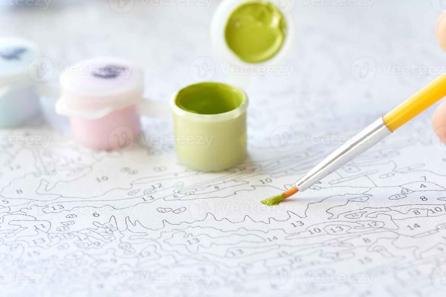 Paint by number art crafting with brush and color pots on patterned canvas for relaxation and creativity. photo