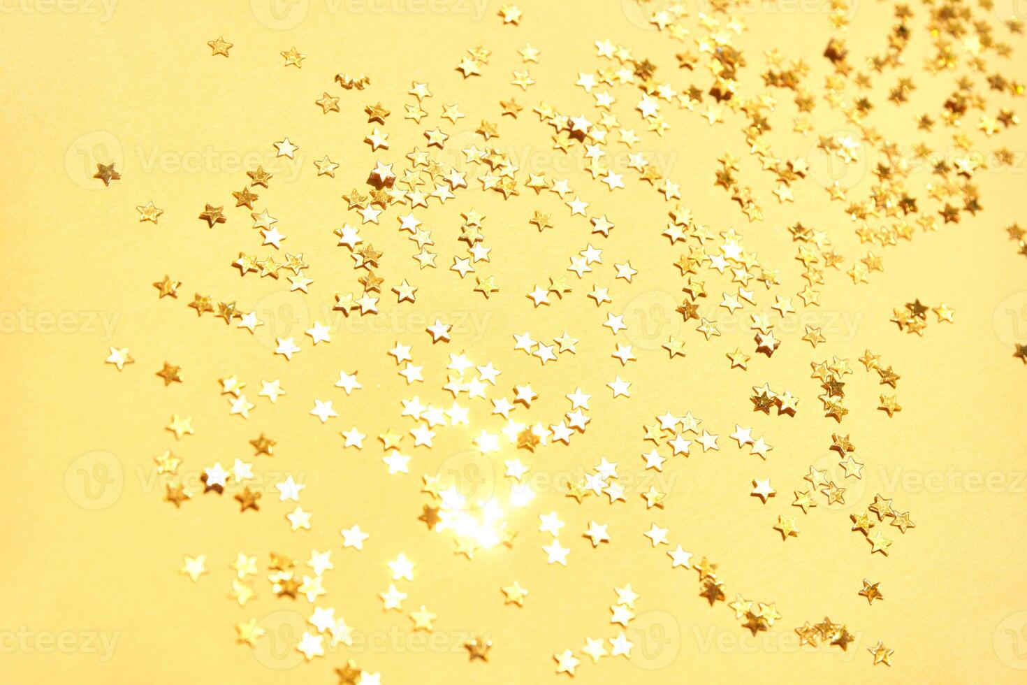 Golden star confetti scattered on yellow background for festive celebration and sparkle themes. photo