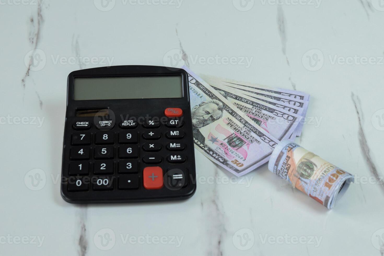 Roll of Dollar banknotes and calculator on the table photo