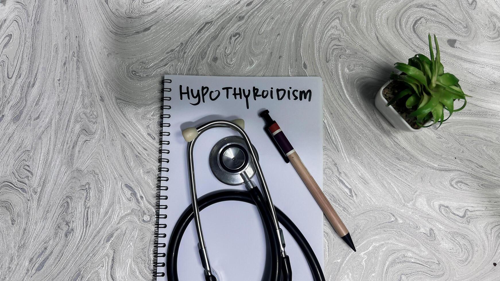 Concept of Hypothyroidism write on book isolated on Wooden Table. photo