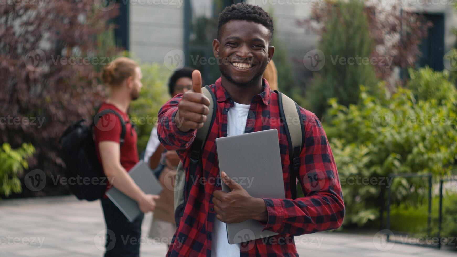 Happy smiling African American student teenager man guy male showing thumb up great cool reaction recommend good education studying enjoy like posing in city university talking multiracial students photo