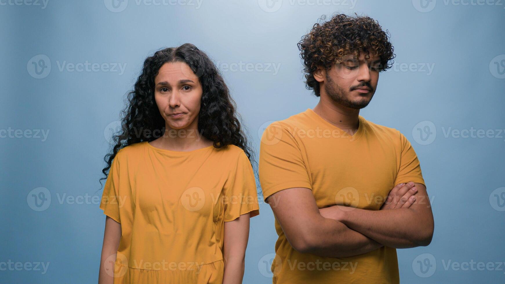 Angry mad Hispanic woman screaming scolds Indian man showing blah blah gesture multiracial couple quarrel argue angry conflict problem family trouble bad relationship offended blue studio background photo