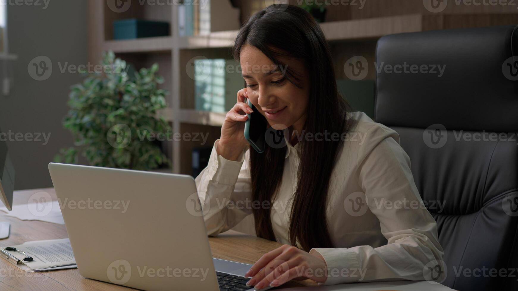 Caucasian business woman multitasking busy in office working online with laptop talking mobile phone smartphone writing documents papers answer call talk with clients multitask businesswoman work photo