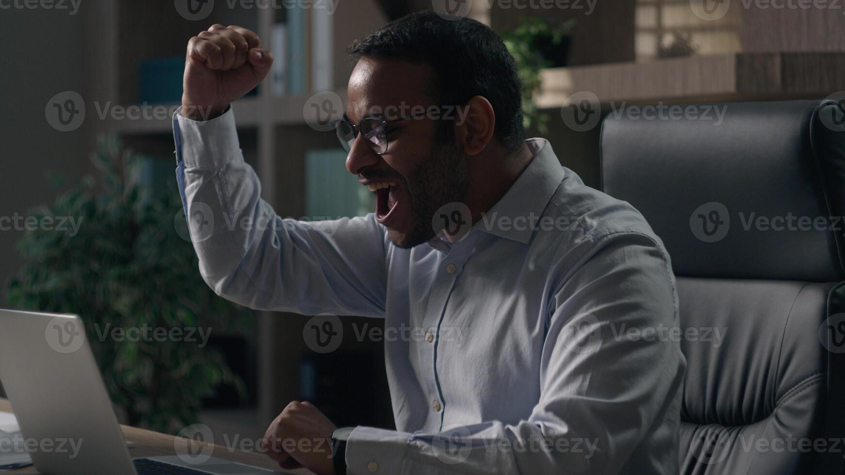 Wonder screaming shouting Indian businessman American man laptop win bet excited unbelievable good news yelling happy emotional executive victory computer winning achieve online success in office photo