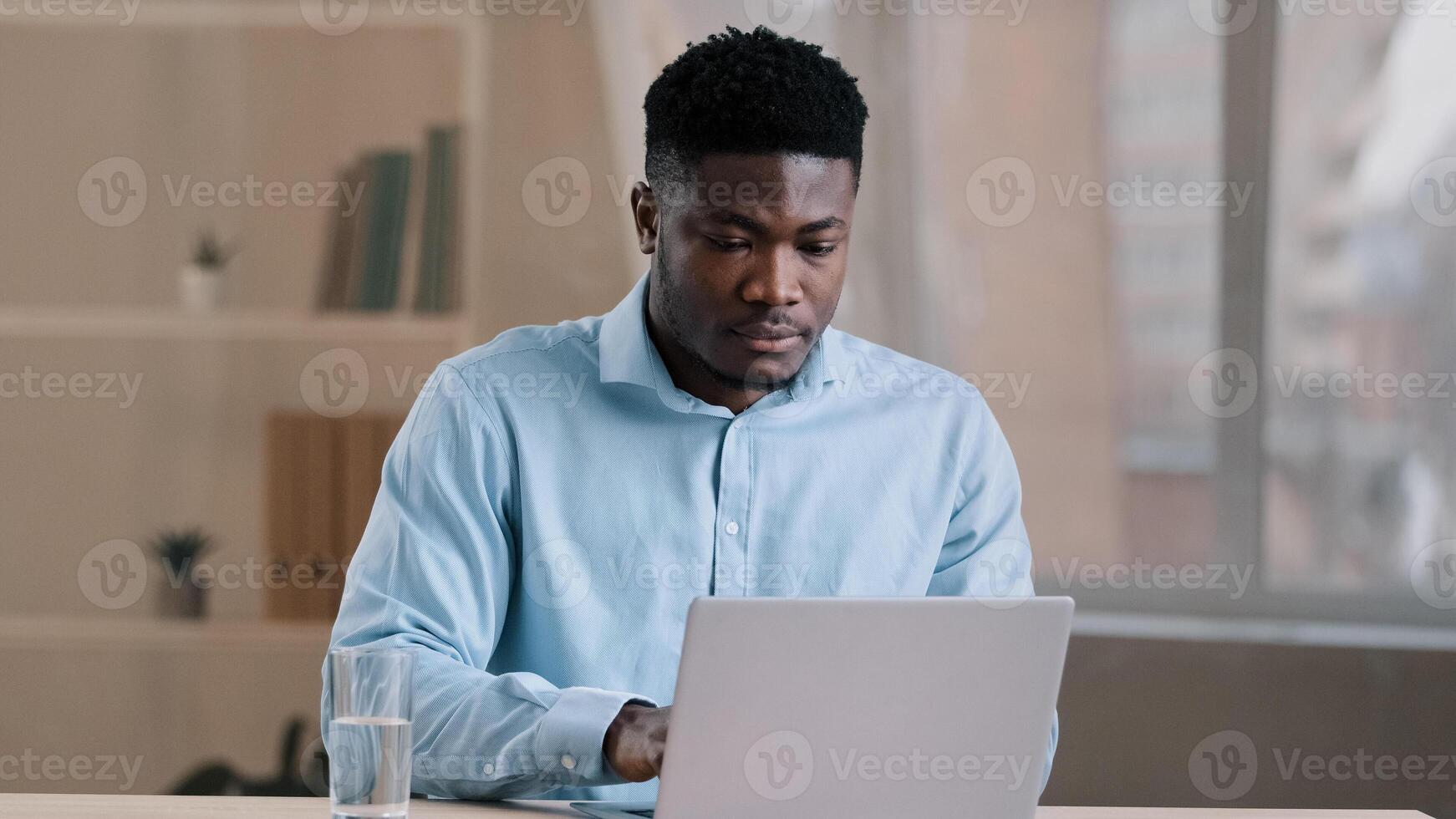 African male busy man worker american businessman guy student sit at home office typing on computer finish online work make daily tasks feel thirsty drink glass of cold fresh water keep health balance photo