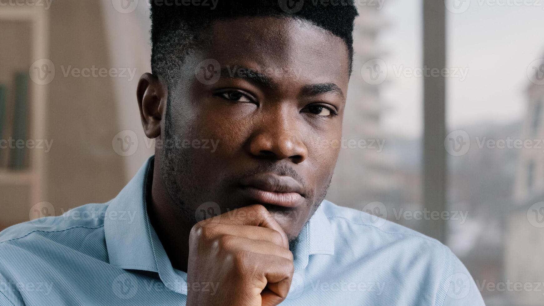 Thoughtful dreamy african man doubtful guy brunet worker businessman hold hand on chin deep in thoughts look distance think about future turns head at camera makes difficult decision nods in agreement photo