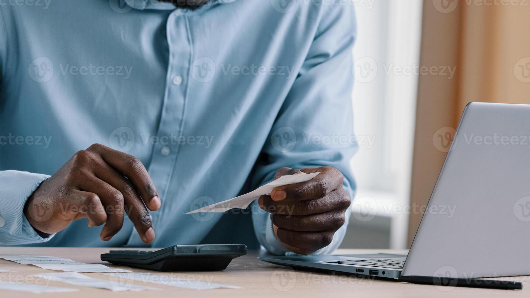 Close up unknown african man banker accountant hold payment incomes outcomes utility bills make calculation of unpaid bank debt make audit check credit balance manage monthly budget reconcile accounts photo