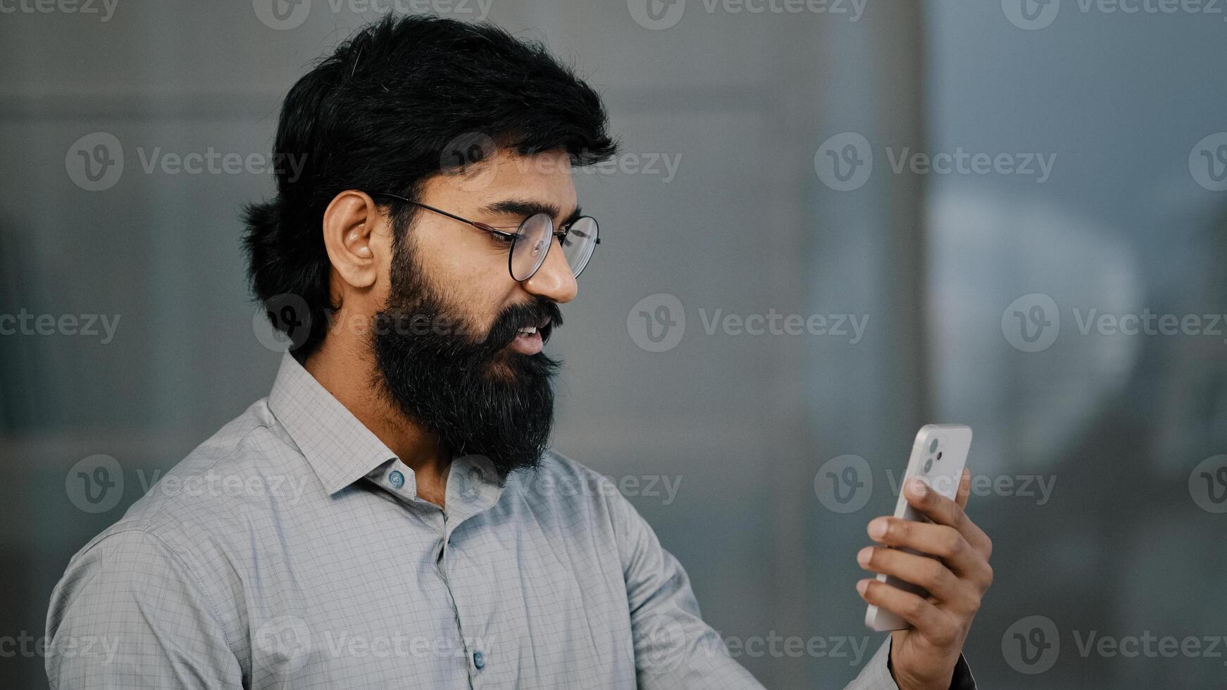 Arab bearded man businessman entrepreneur investor hold communication with business partners friends discussing project online remote conference general worker making call use smartphone indoor photo