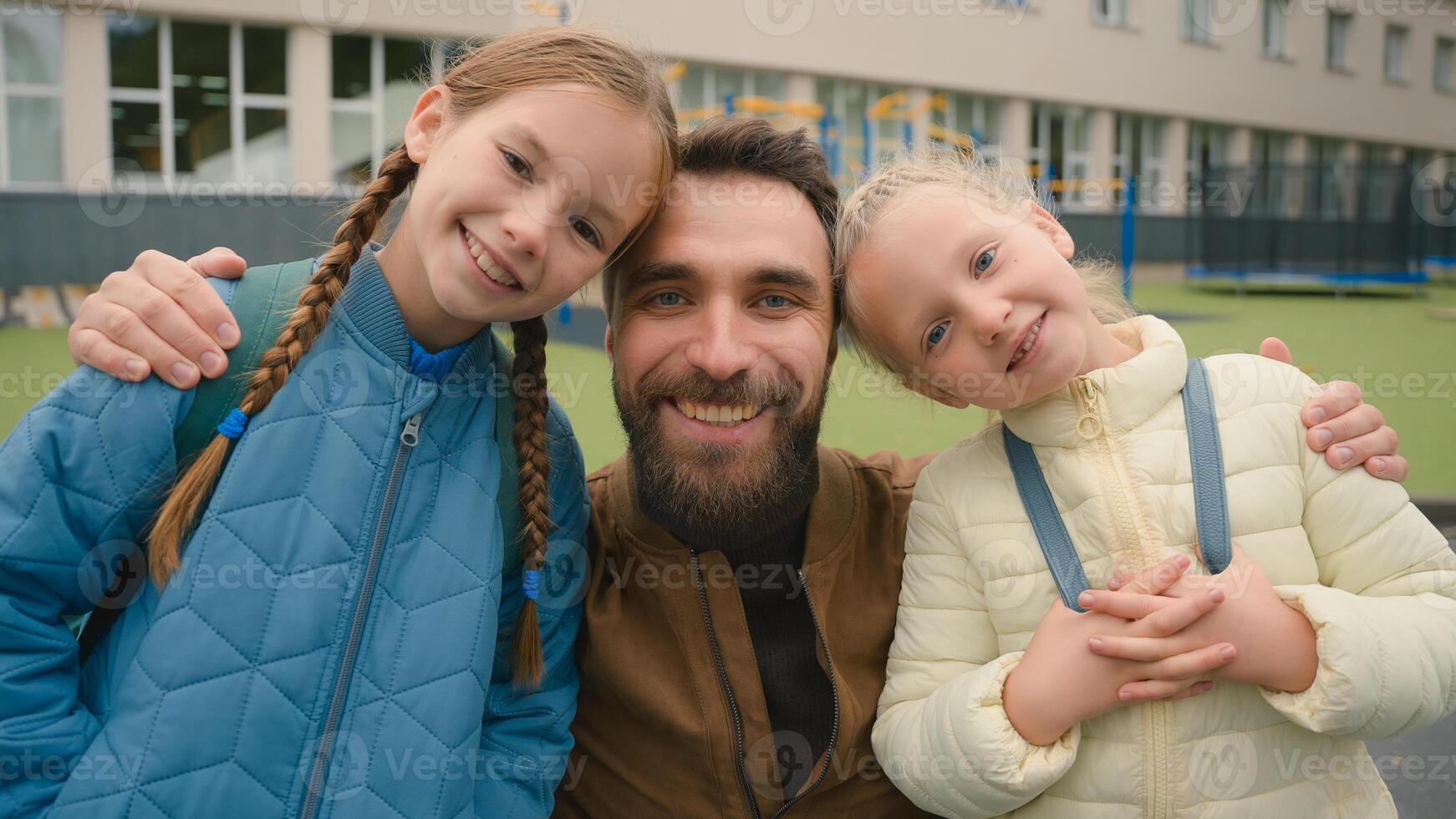 Close up happy family European man two girls kids father parent daughters smiling little sisters primary school joyful fun together hugging city outside street love children bonding affection portrait photo