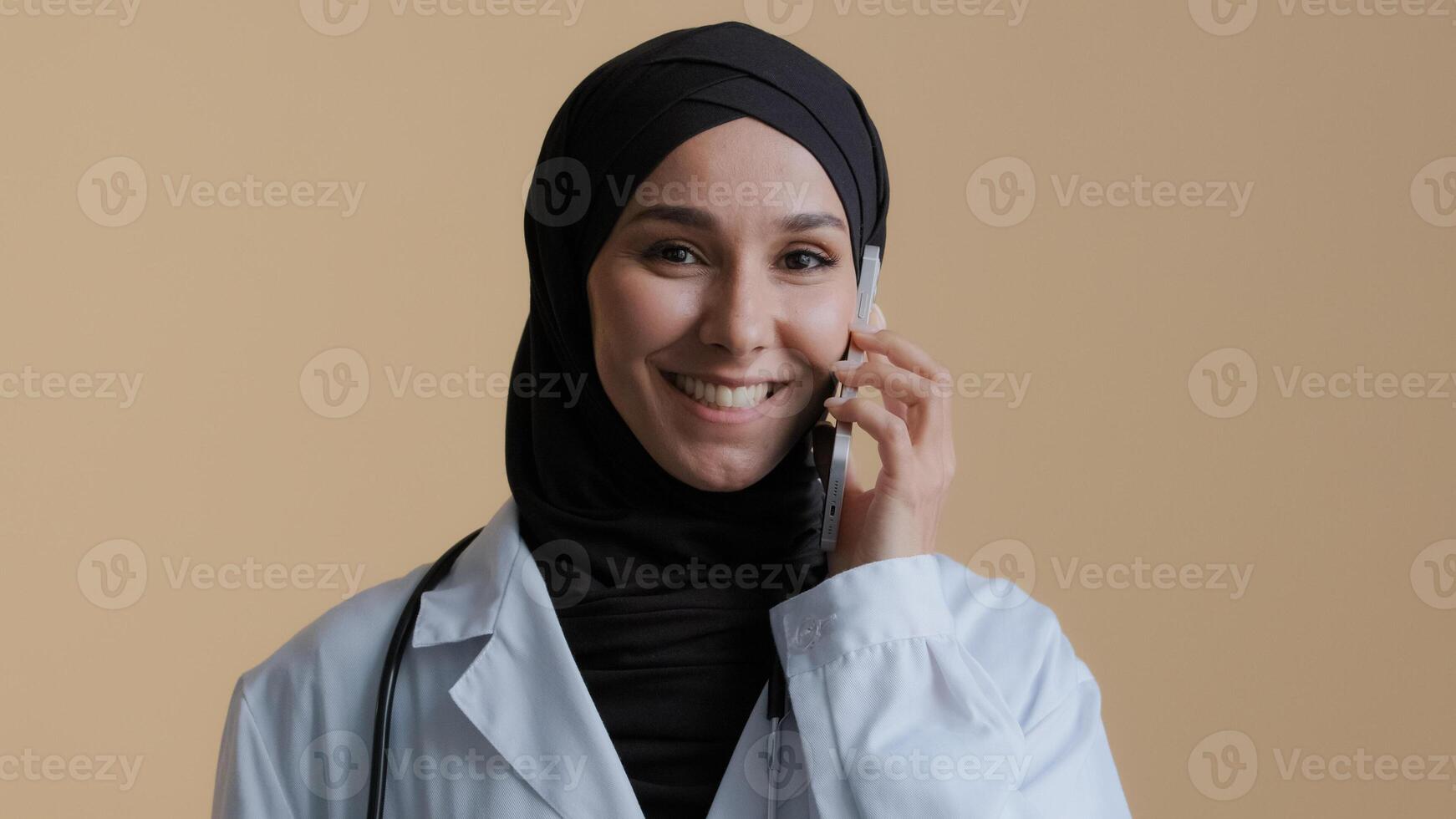 Muslim islamic doctor young intern arab woman surgeon intern in hijab wear medical coat talk by cellphone with patient female advisor consult distant virtual mobile communication health care concept photo