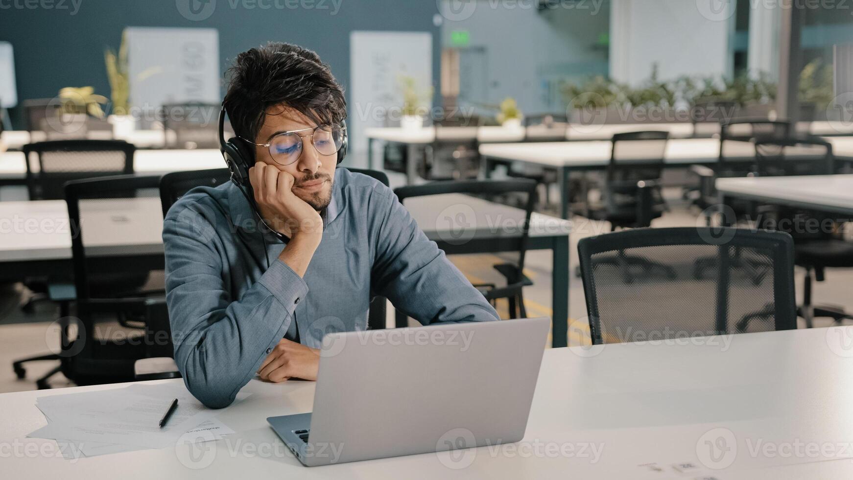 Bored man Arabian man Indian service manager in headphones have displeased look conference webinar learn language improve self-education professional skills studying with difficult task boredom photo