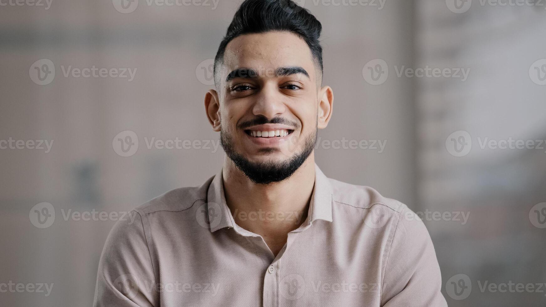 Happy joyful guy hispanic arabian handsome young man casual model with toothy smile look at camera optimistic male face portrait smiling businessman intelligent millennial posing indoors close up view photo