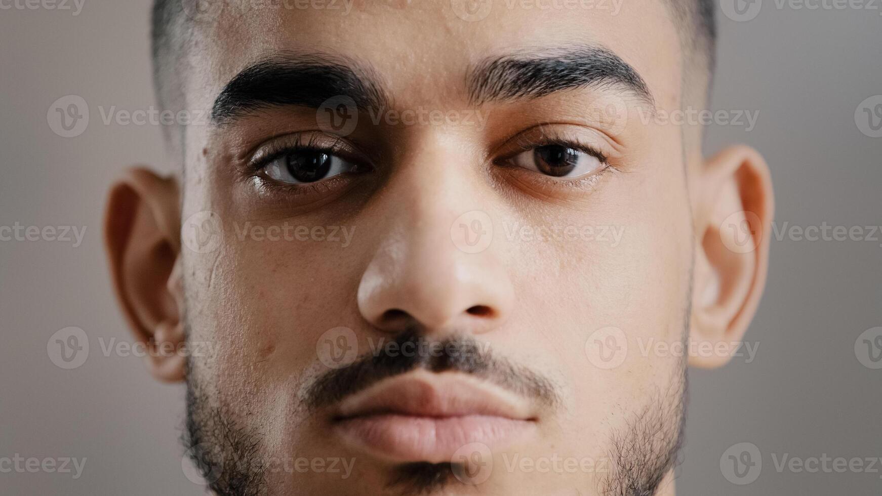 Close-up portrait of hispanic indian male serious young student man freelancer model stand indoor posing at camera with confident deep look millennial ethnic handsome brunet guy show facial expression photo