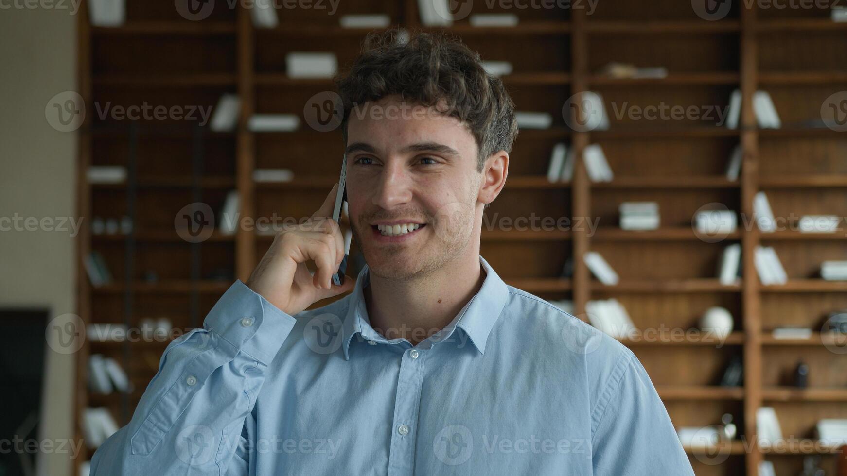 Glad positive successful Caucasian man male guy businessman talking speak online mobile phone call consulting client cellphone discussion solving business question friendly conversation indoors office photo