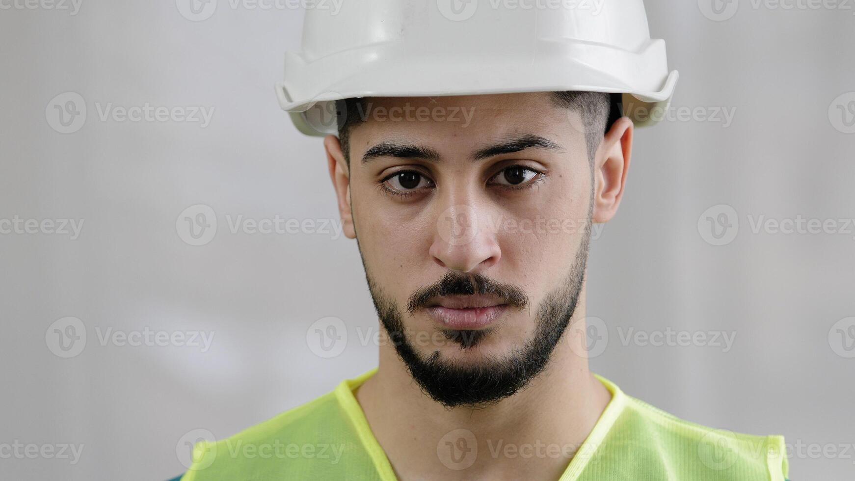 Close-up portrait of serious arabian man male foreman professional inspector builder mechanic engineer wear uniform safety helmet posing at camera looking confident eyesight inspect manufacture work photo